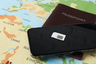 SIM card, smartphone and passport on world map, closeup