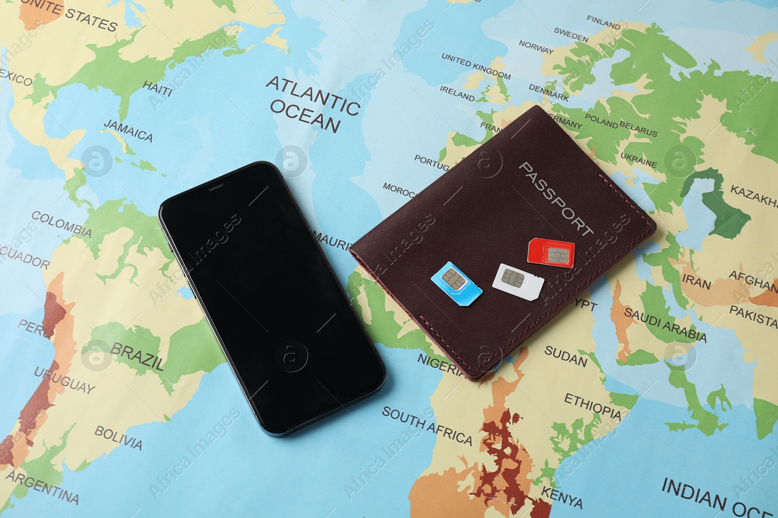 Photo of SIM cards, smartphone and passport on world map, flat lay