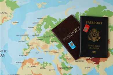 SIM cards and passports on world map, flat lay