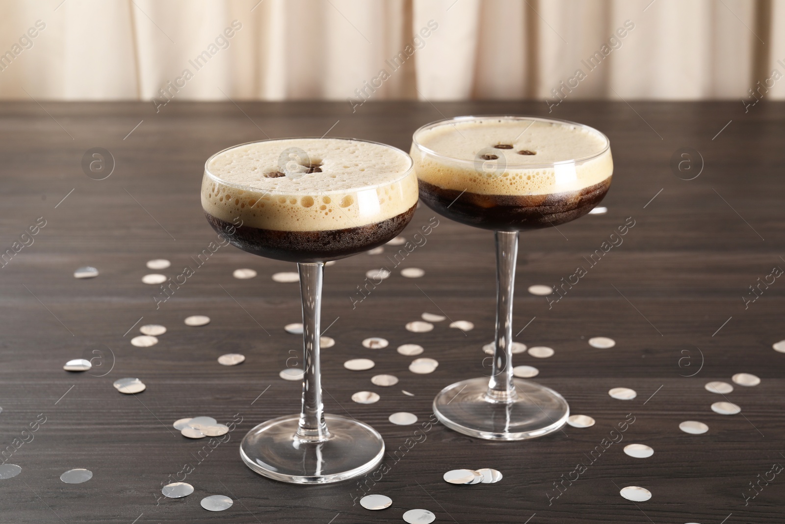 Photo of Fresh coffee cocktails in glasses and confetti on wooden table