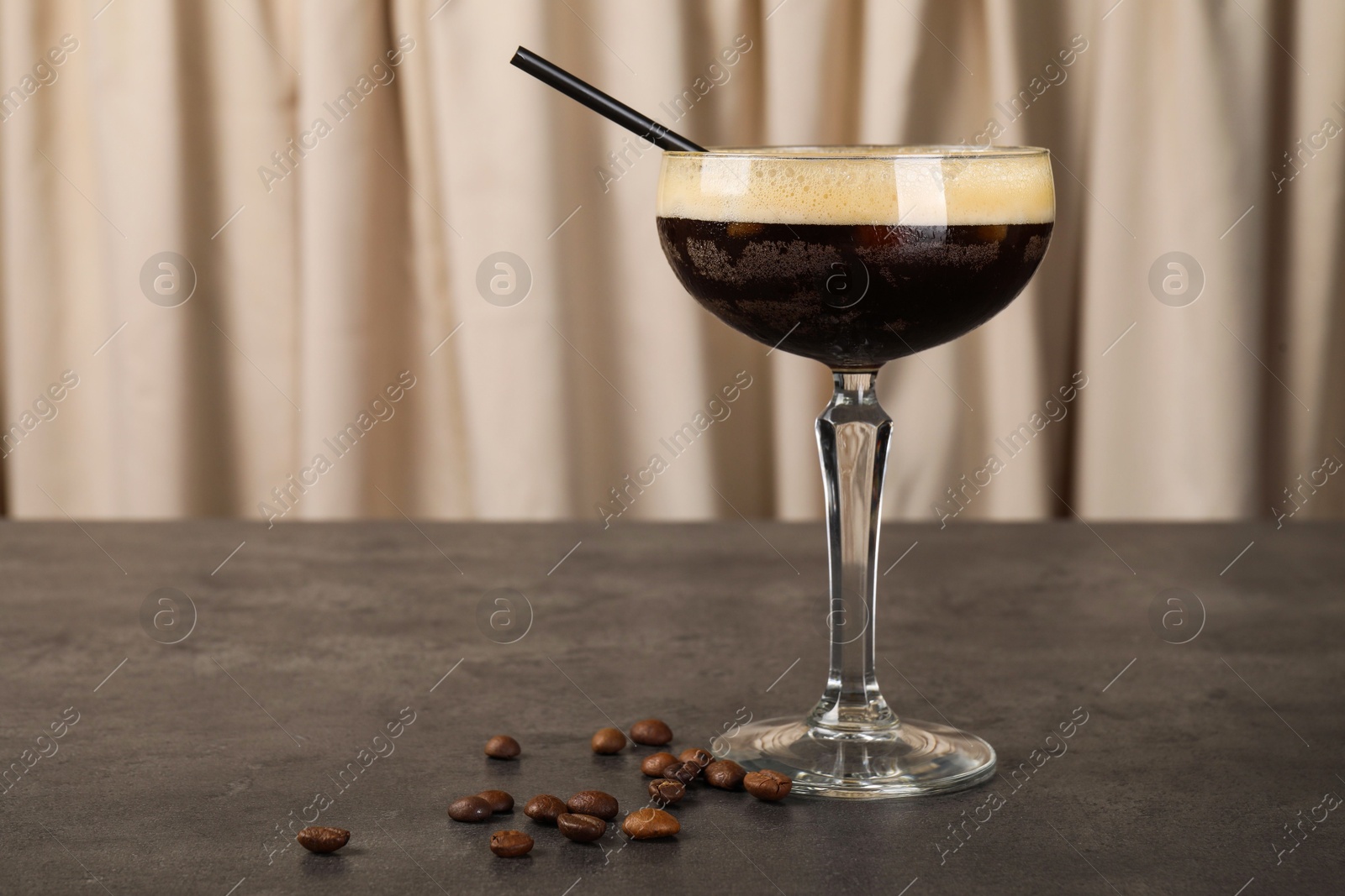 Photo of Fresh coffee cocktail in glass and beans on grey table. Space for text