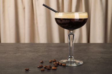 Photo of Fresh coffee cocktail in glass and beans on grey table. Space for text