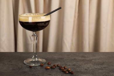 Photo of Fresh coffee cocktail in glass and beans on grey table, space for text