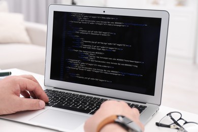 Photo of Programmer working with laptop at white desk in office, closeup