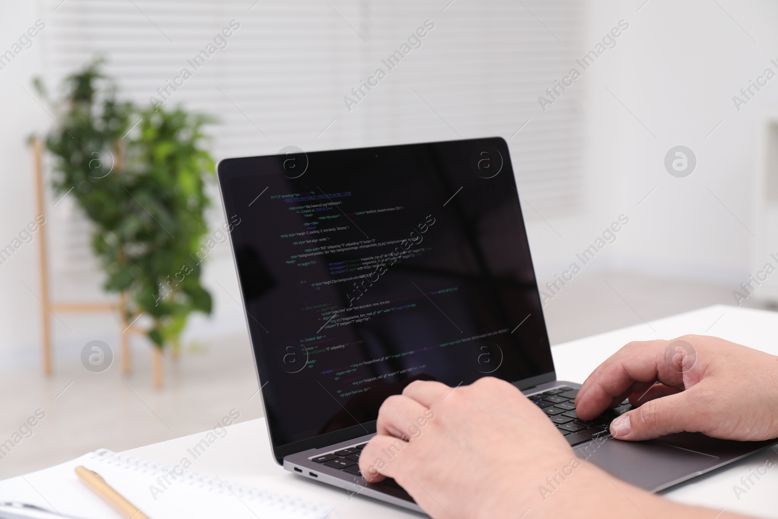 Photo of Programmer working with laptop at white desk in office, closeup