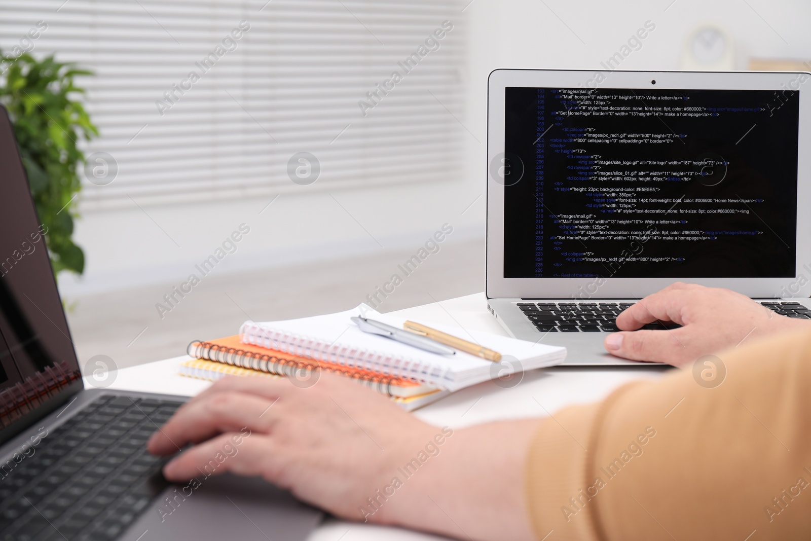 Photo of Programmer working with laptop at white desk in office, closeup