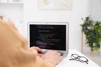 Photo of Programmer working with laptop at white desk in office, closeup