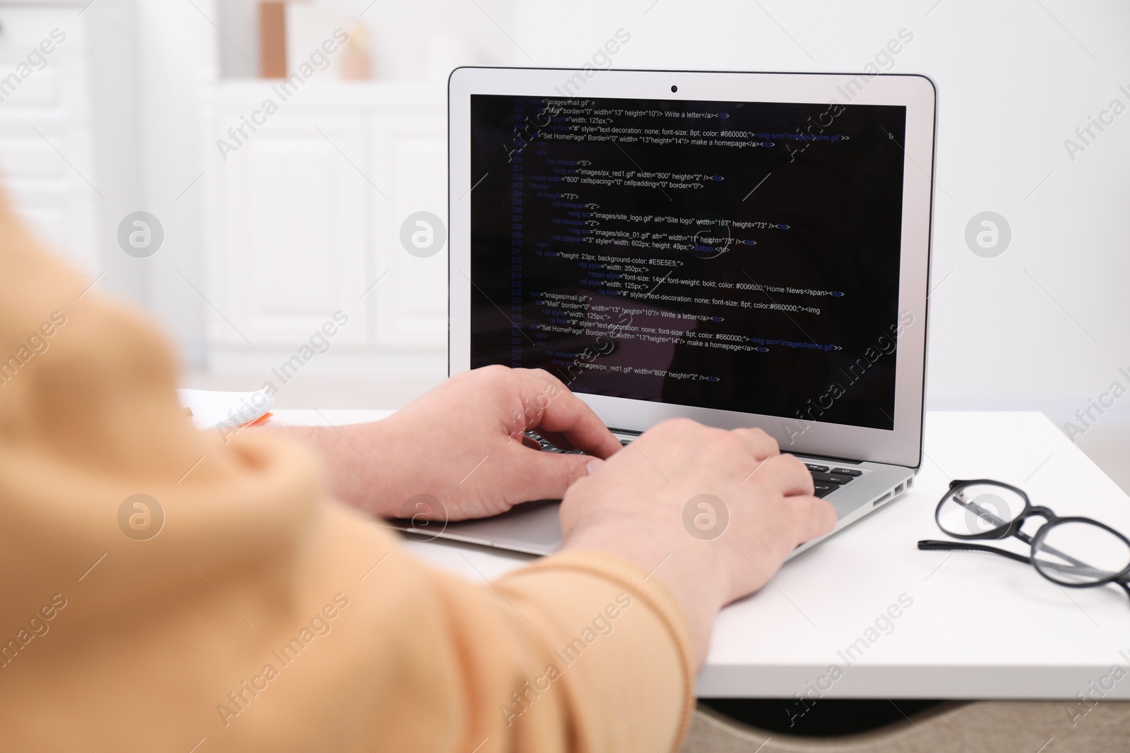 Photo of Programmer working with laptop at desk in office, closeup