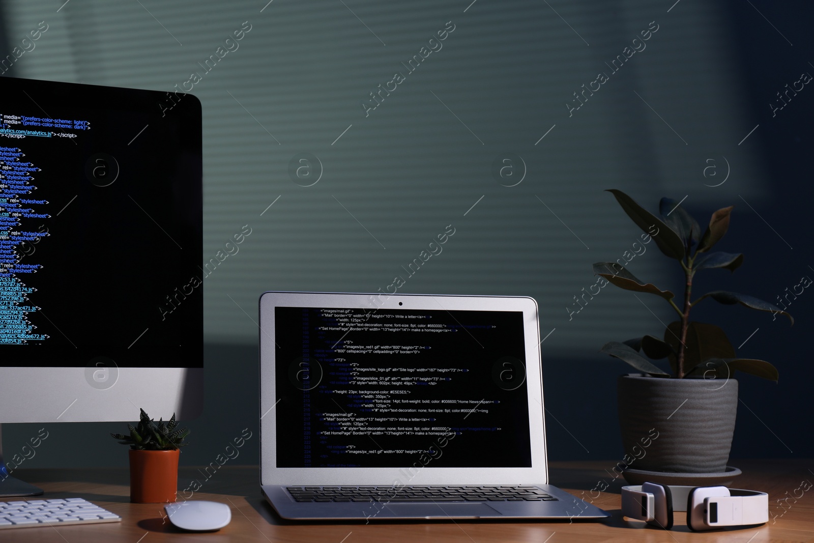 Photo of Programmer's workplace. Modern computer with unfinished code, laptop and other supplies on wooden desk