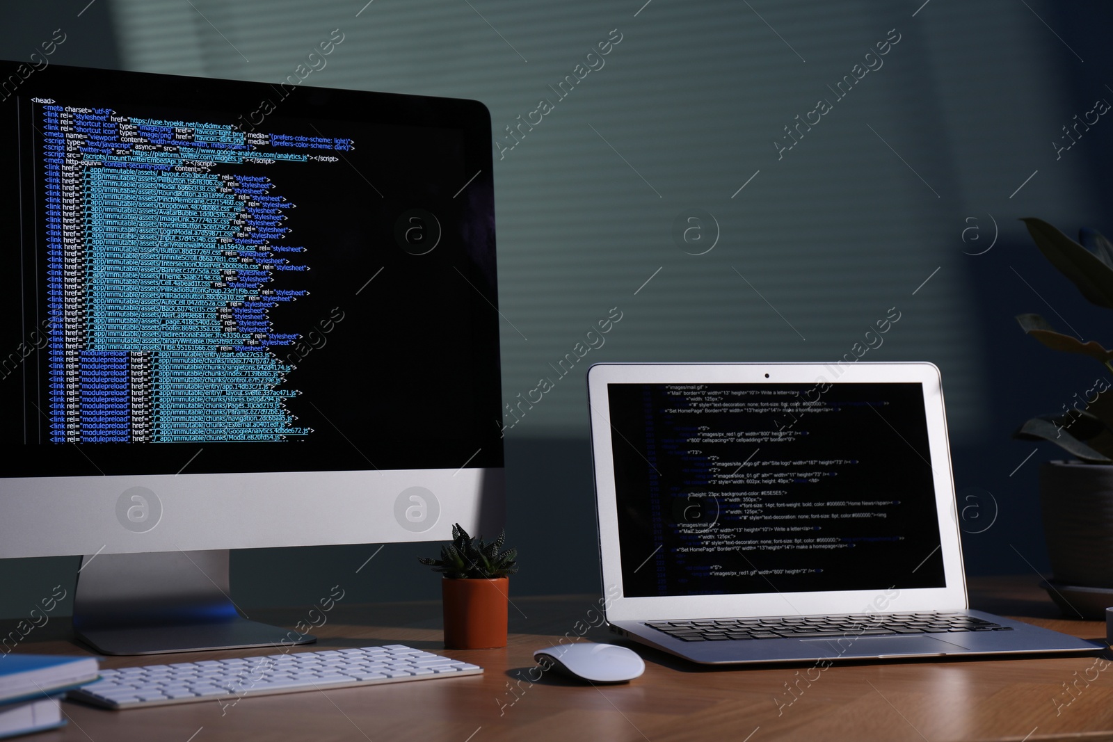 Photo of Programmer's workplace. Modern computer with unfinished code, laptop and other supplies on wooden desk