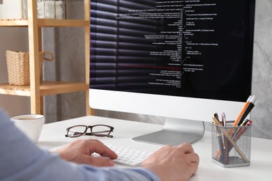 Photo of Programmer working with computer at white desk in office, closeup