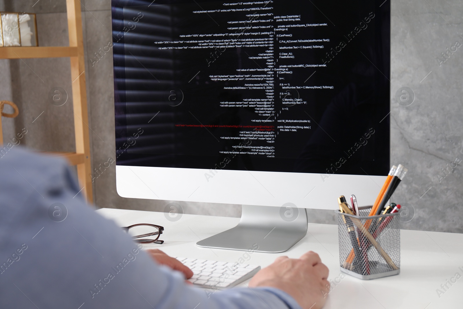 Photo of Programmer working with computer at white desk in office, closeup