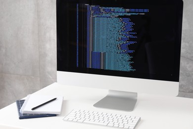 Photo of Programmer's workplace. Modern computer with unfinished code and stationery on desk indoors