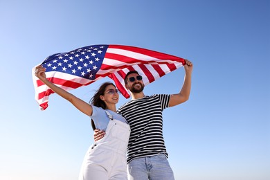 Photo of Happy couple with flag of USA outdoors, low angle view