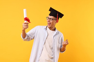 Photo of Happy student with diploma after graduation on orange background