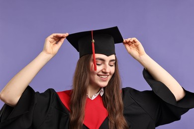 Photo of Happy student after graduation on violet background