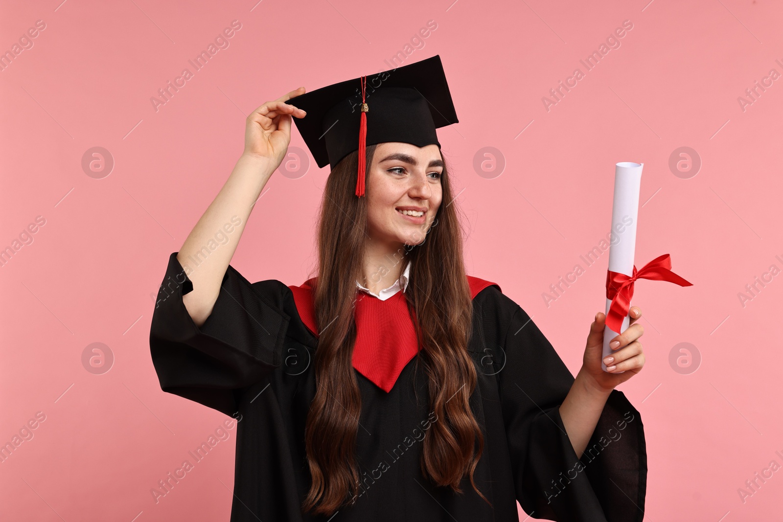 Photo of Happy student with diploma after graduation on pink background