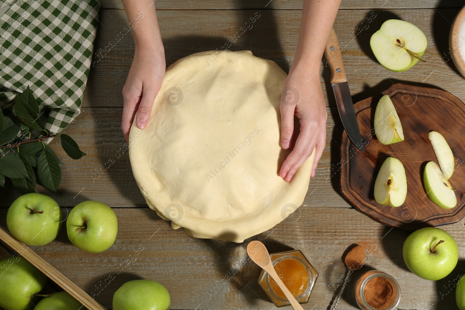 Photo of Woman making homemade apple pie at wooden table, top view