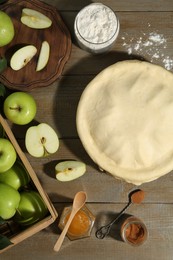 Photo of Raw homemade apple pie and ingredients on wooden table, flat lay