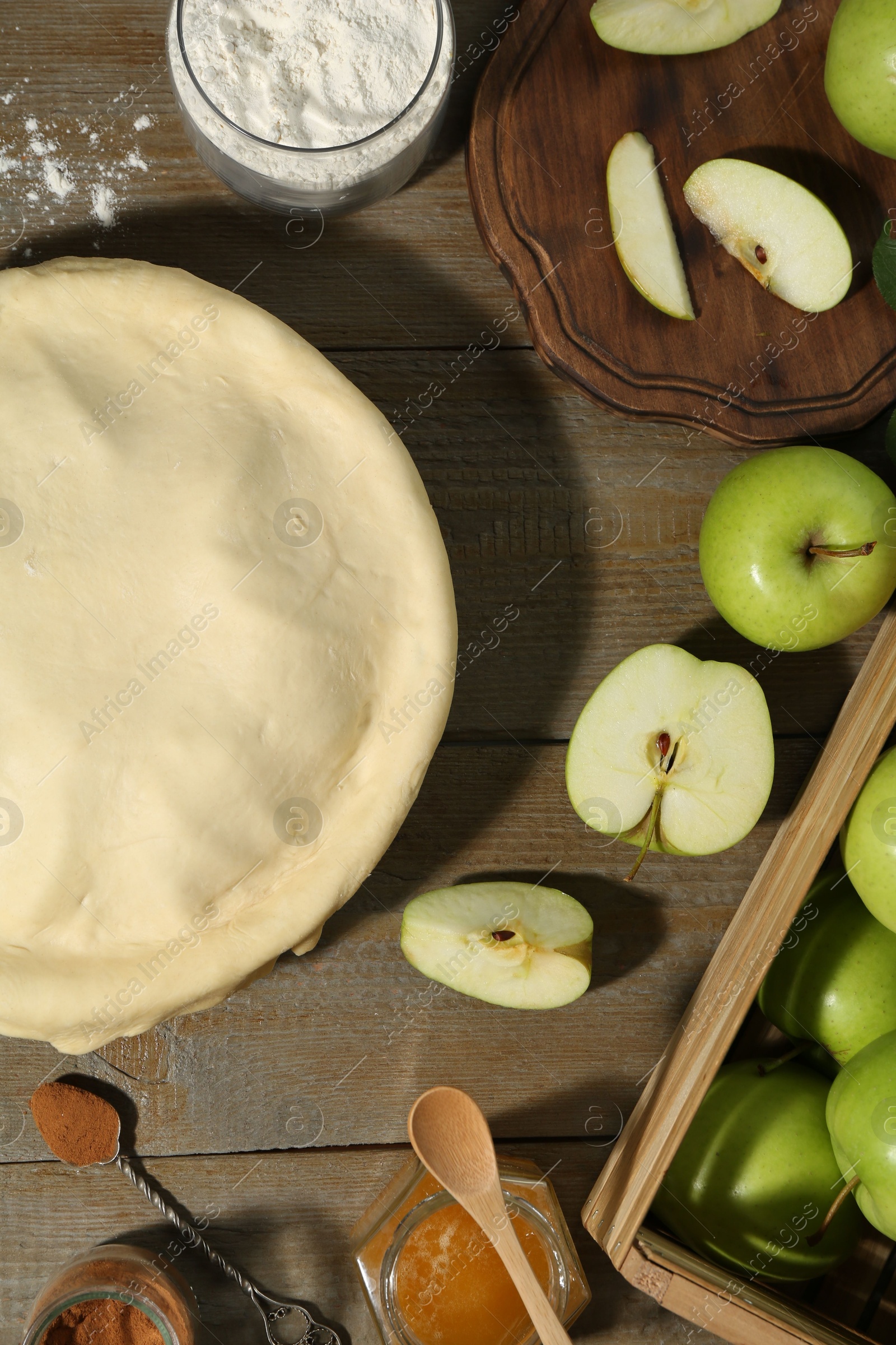 Photo of Raw homemade apple pie and ingredients on wooden table, flat lay