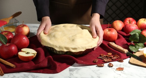 Woman making homemade apple pie at white marble table, closeup