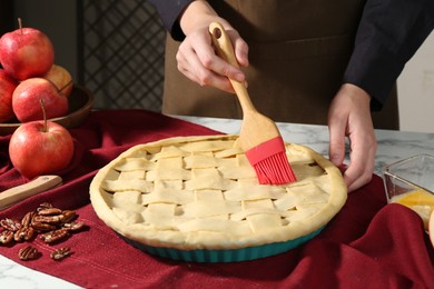 Photo of Woman making homemade apple pie at white marble table, closeup