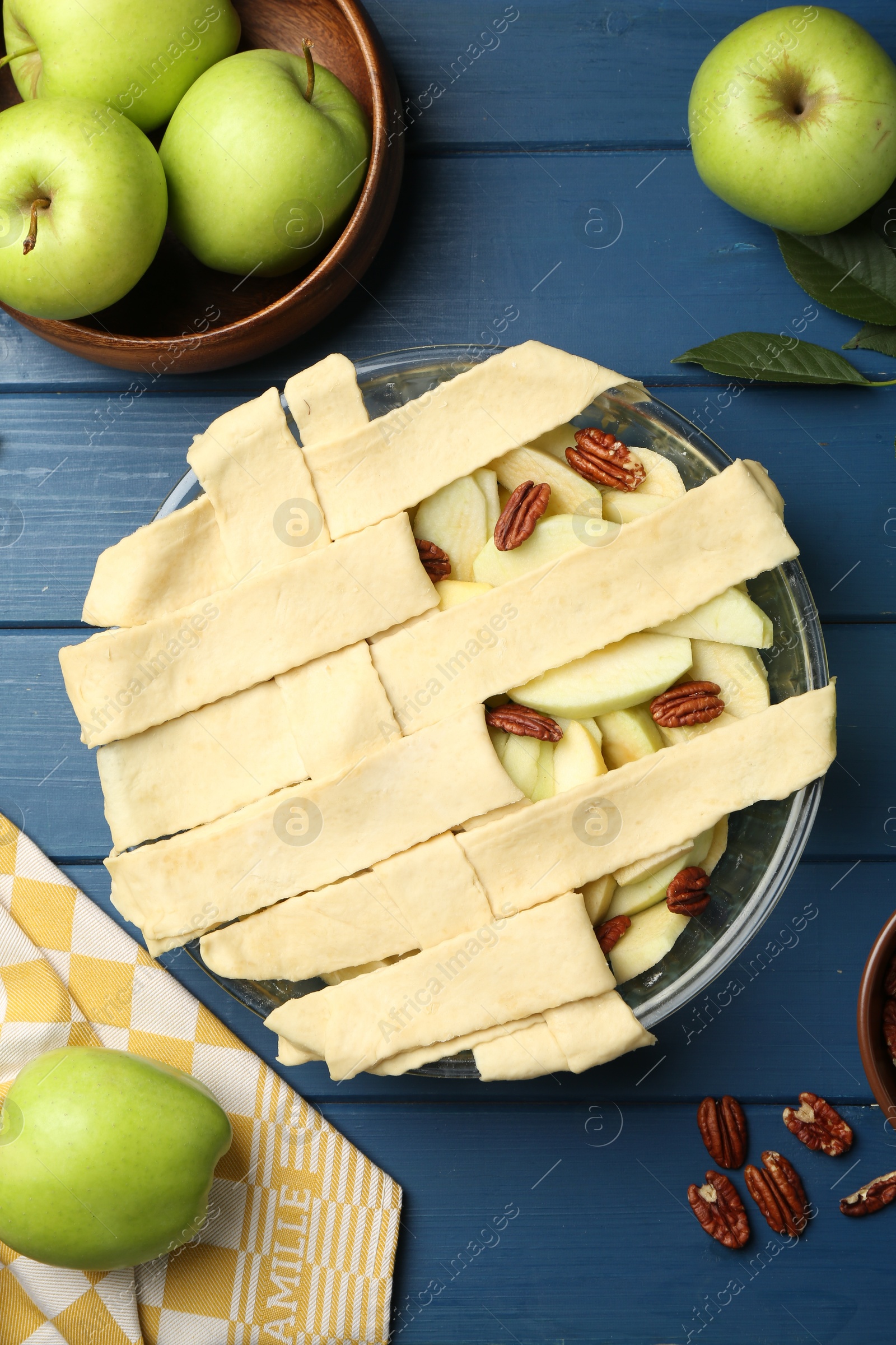 Photo of Flat lay composition with raw homemade apple pie and ingredients on blue wooden table