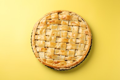 Photo of Tasty homemade pie on yellow background, top view