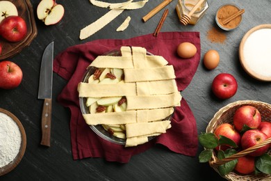 Photo of Flat lay composition with raw homemade apple pie and ingredients on dark textured table