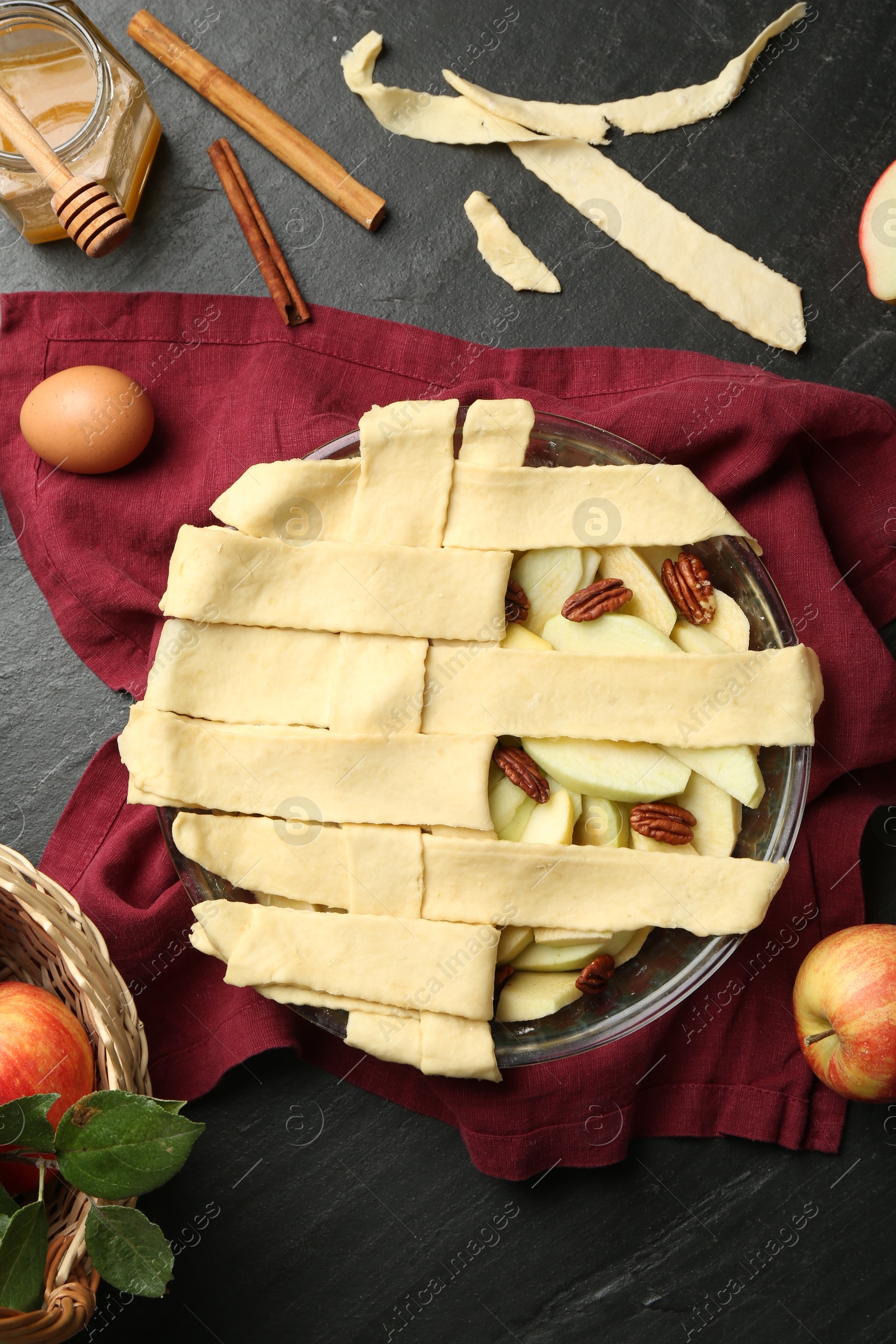 Photo of Flat lay composition with raw homemade apple pie and ingredients on dark textured table