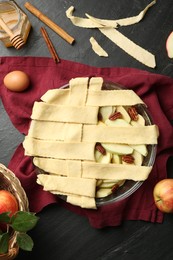 Photo of Flat lay composition with raw homemade apple pie and ingredients on dark textured table