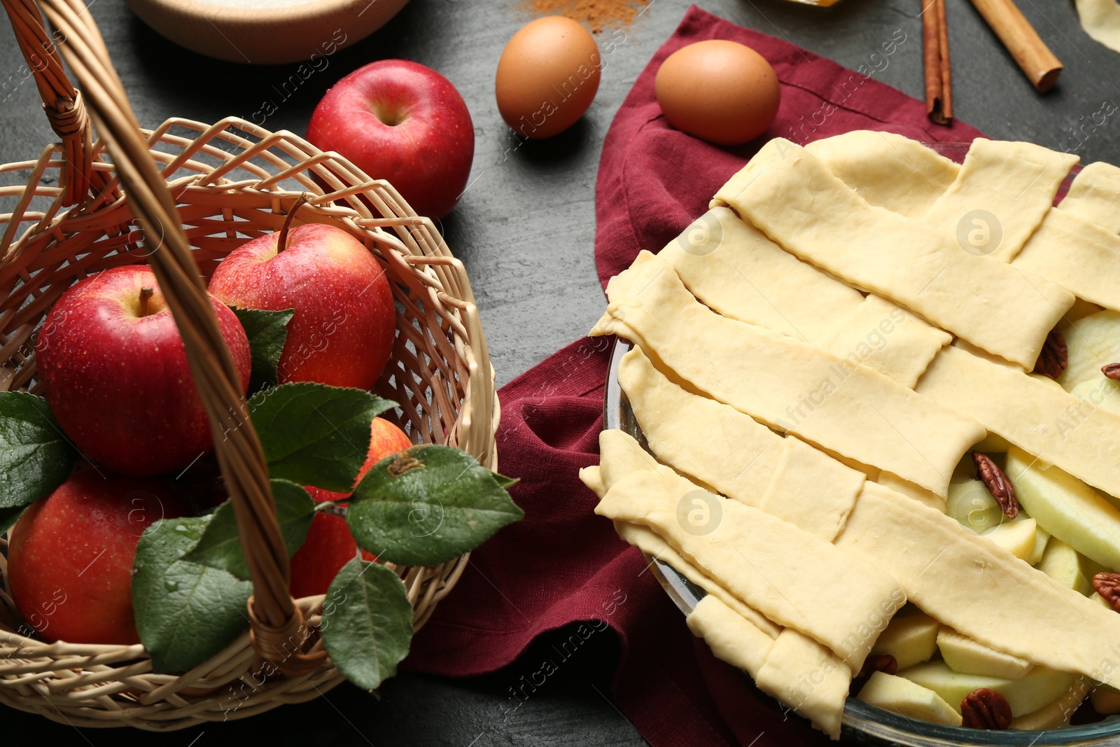 Photo of Raw homemade apple pie and ingredients on dark textured table