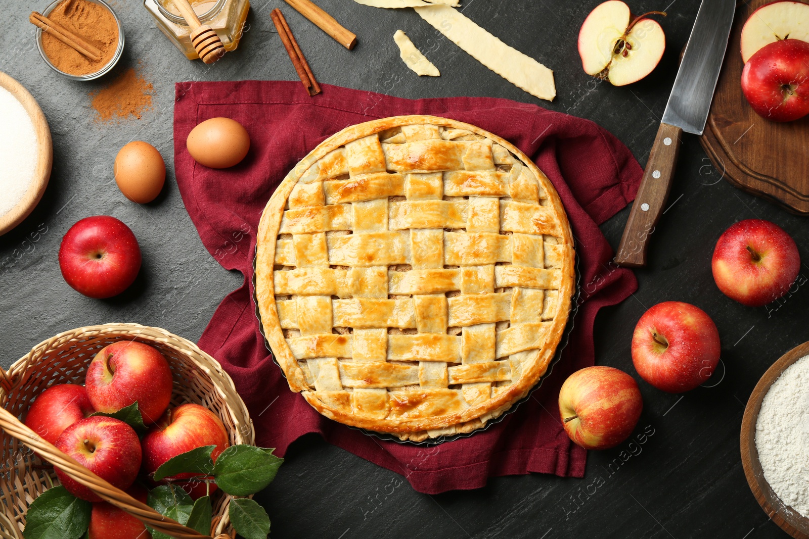 Photo of Flat lay composition with tasty homemade apple pie and ingredients on dark textured table