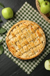 Photo of Flat lay composition with tasty homemade apple pie and ingredients on dark textured table