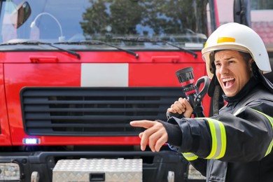 Photo of Firefighter in uniform with high pressure water jet near fire truck outdoors