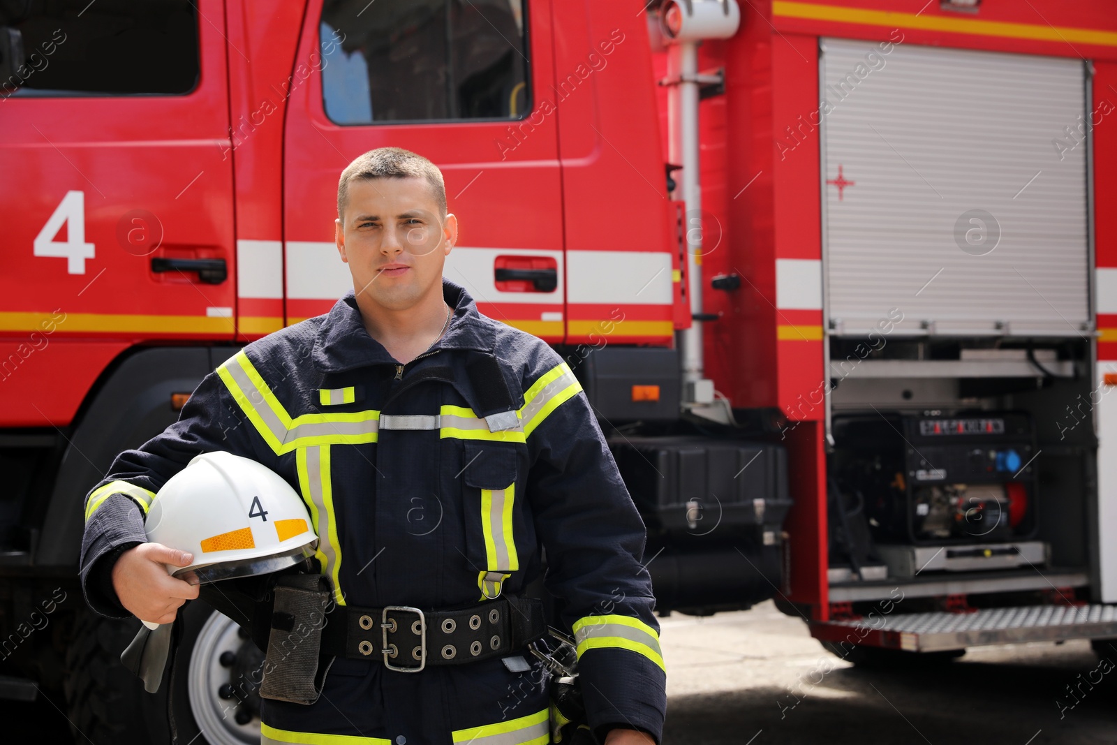 Photo of Portrait of firefighter in uniform with helmet near fire truck outdoors