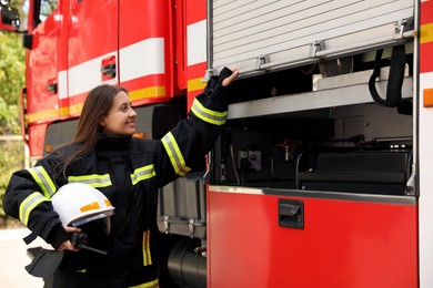 Photo of Portrait of firefighter in uniform with helmet near fire truck outdoors