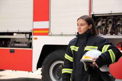 Portrait of firefighter in uniform with helmet near fire truck outdoors