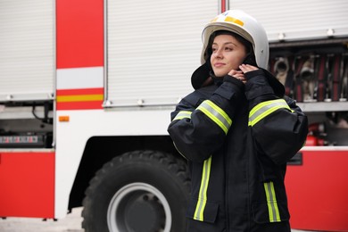 Photo of Firefighter in uniform wearing helmet near fire truck outdoors