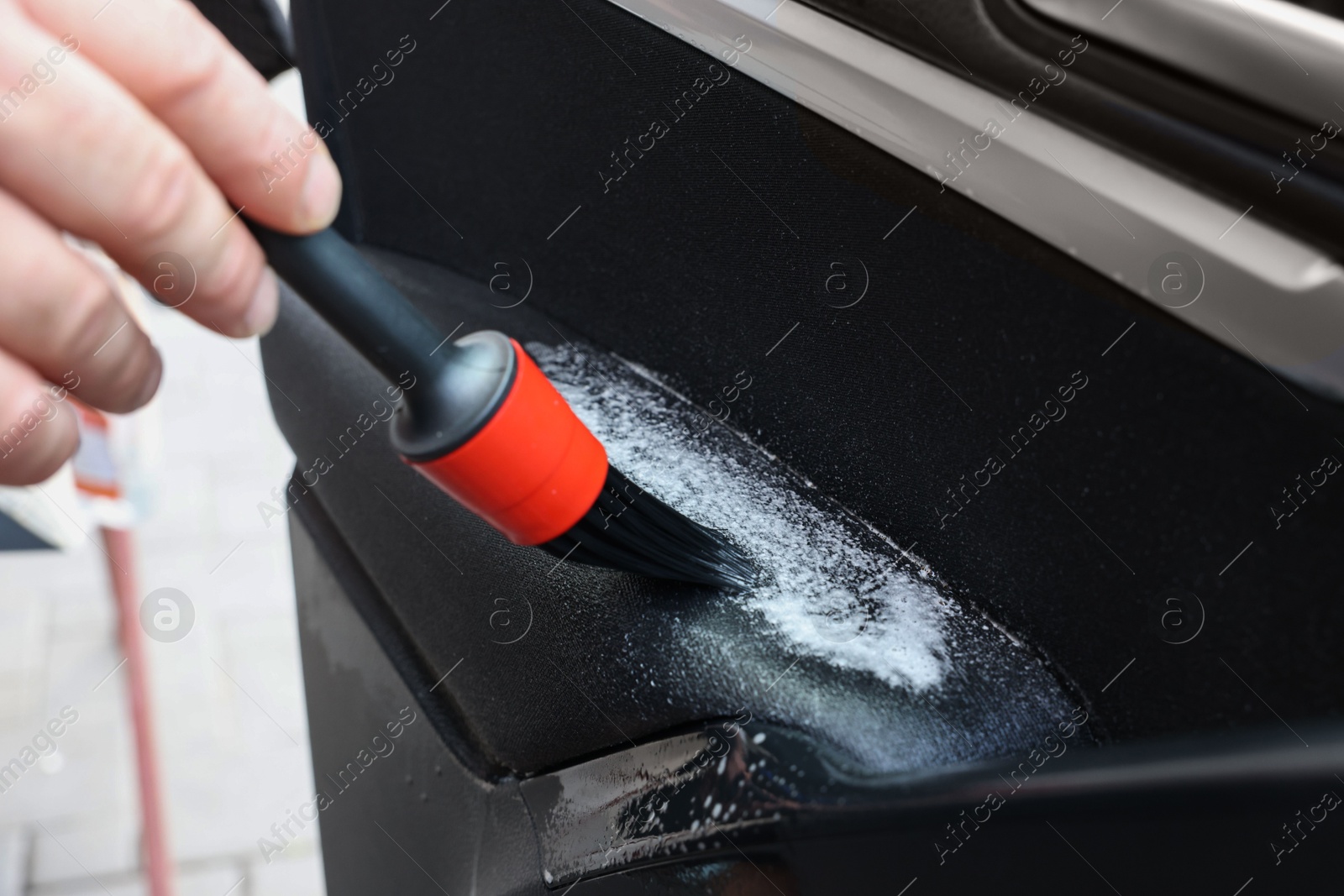 Photo of Man cleaning car door with brush, closeup