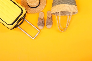 Photo of Suitcase with wicker hat, bag and shoes on yellow background, flat lay. Space for text