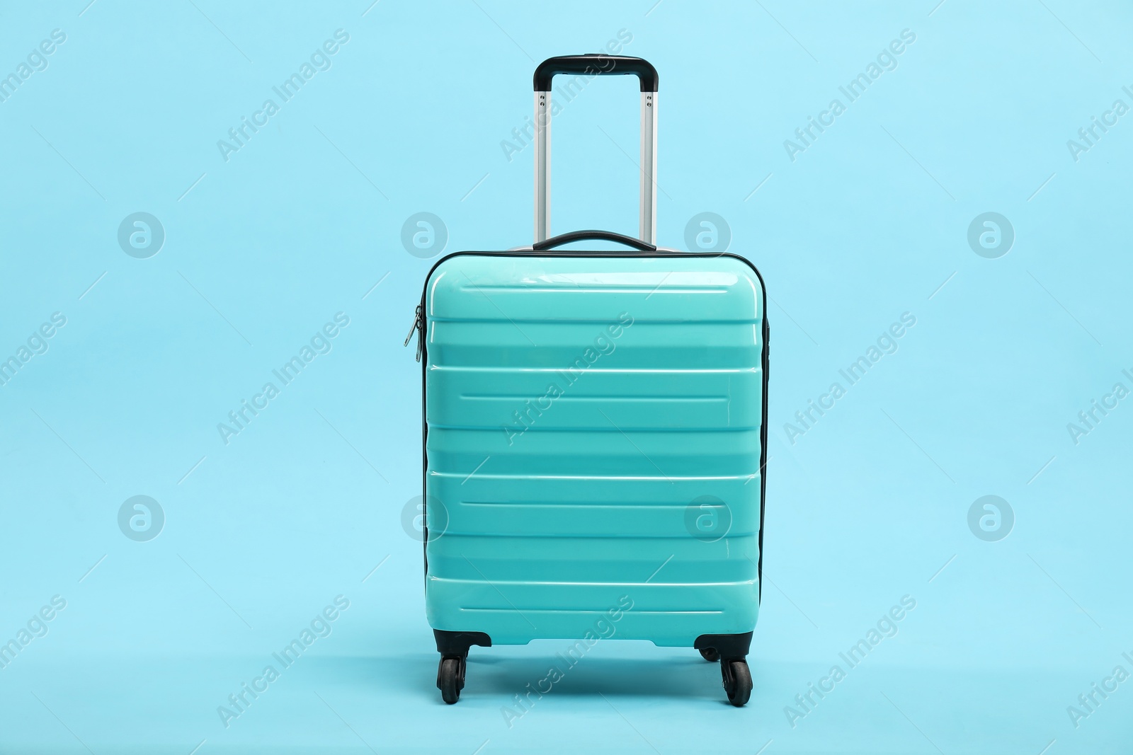 Photo of One new turquoise suitcase on light blue background