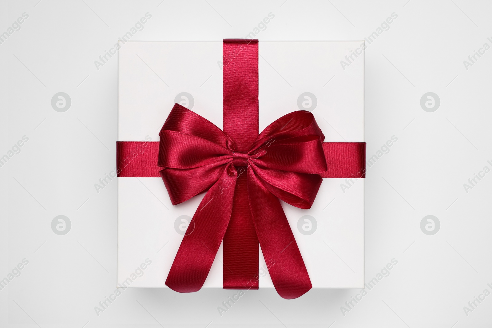 Photo of Gift box with red bow on light grey background, top view