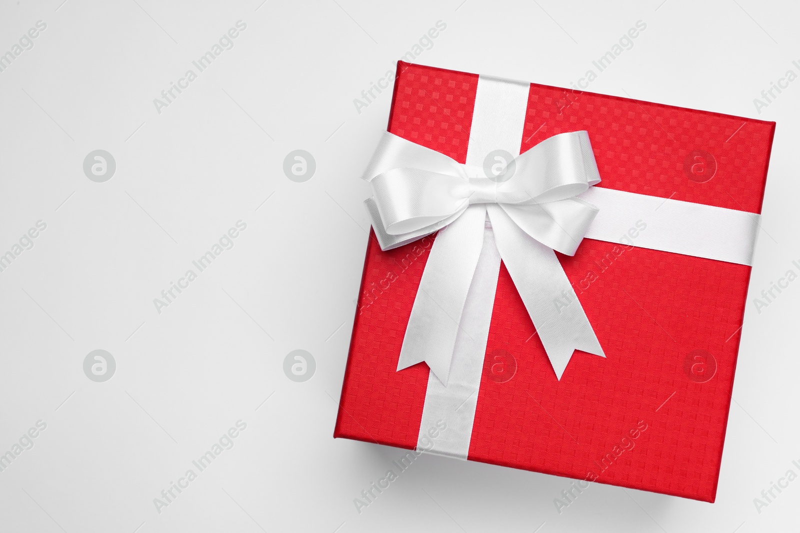 Photo of Gift box with bow on light grey background, top view. Space for text