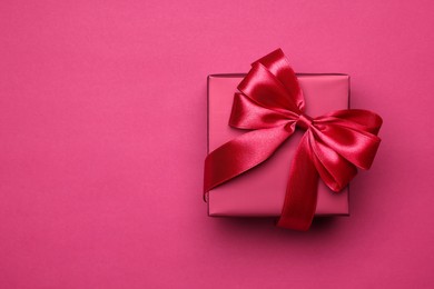 Photo of Gift box with bow on pink background, top view. Space for text