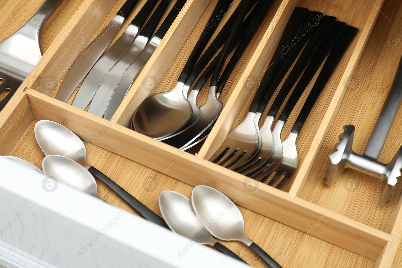 Photo of Cutlery in wooden box, closeup. Kitchen utensils storage