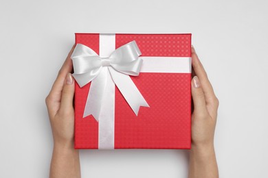 Photo of Woman holding gift box with bow on white background, top view