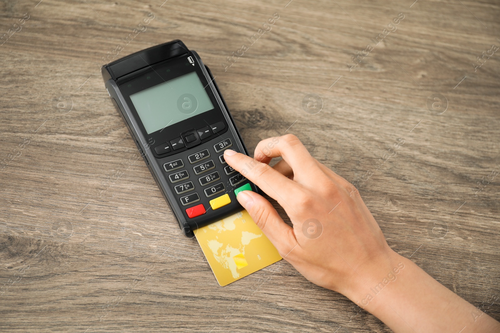 Photo of Woman with credit card using payment terminal at wooden table indoors, top view