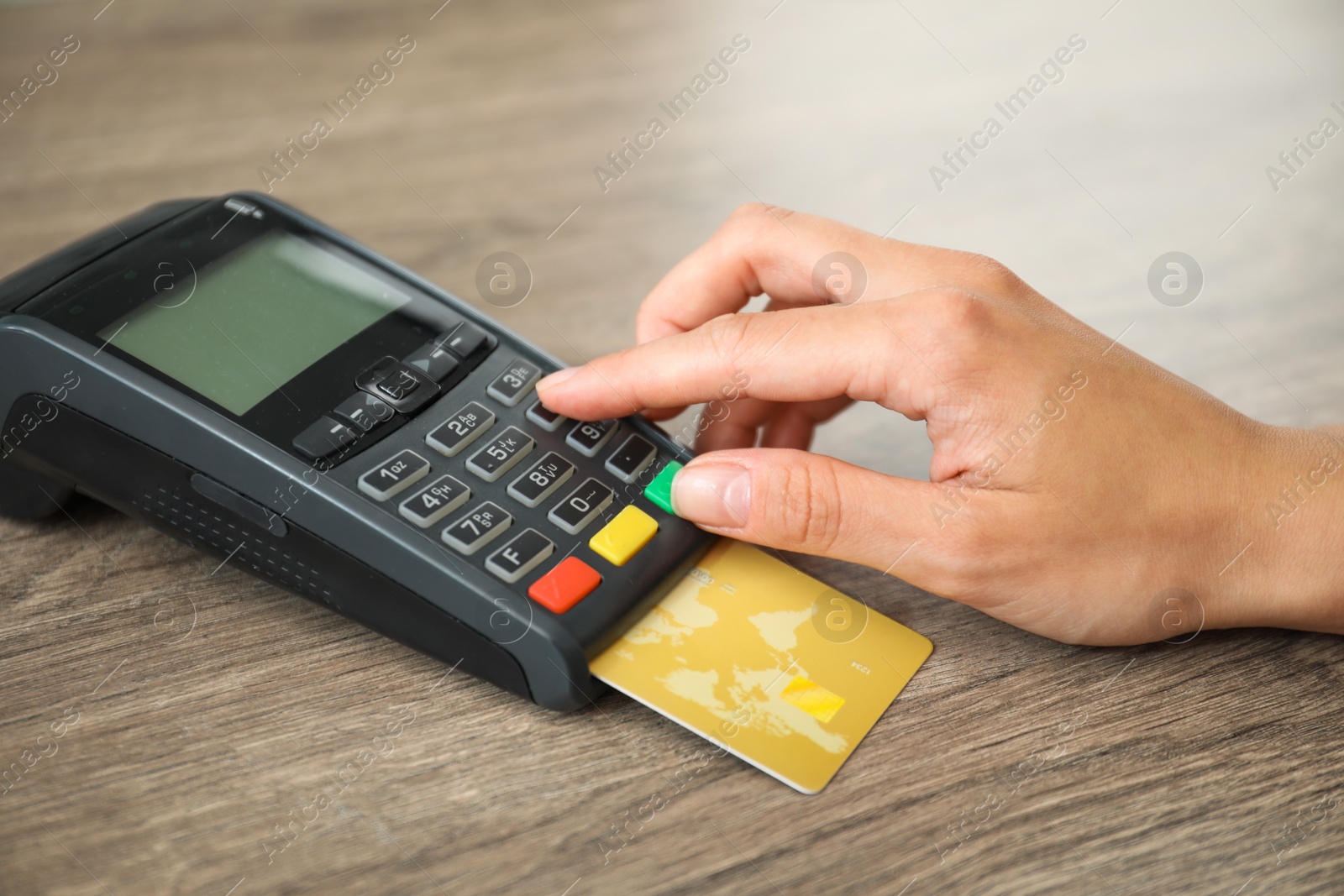 Photo of Woman with credit card using payment terminal at wooden table indoors, closeup