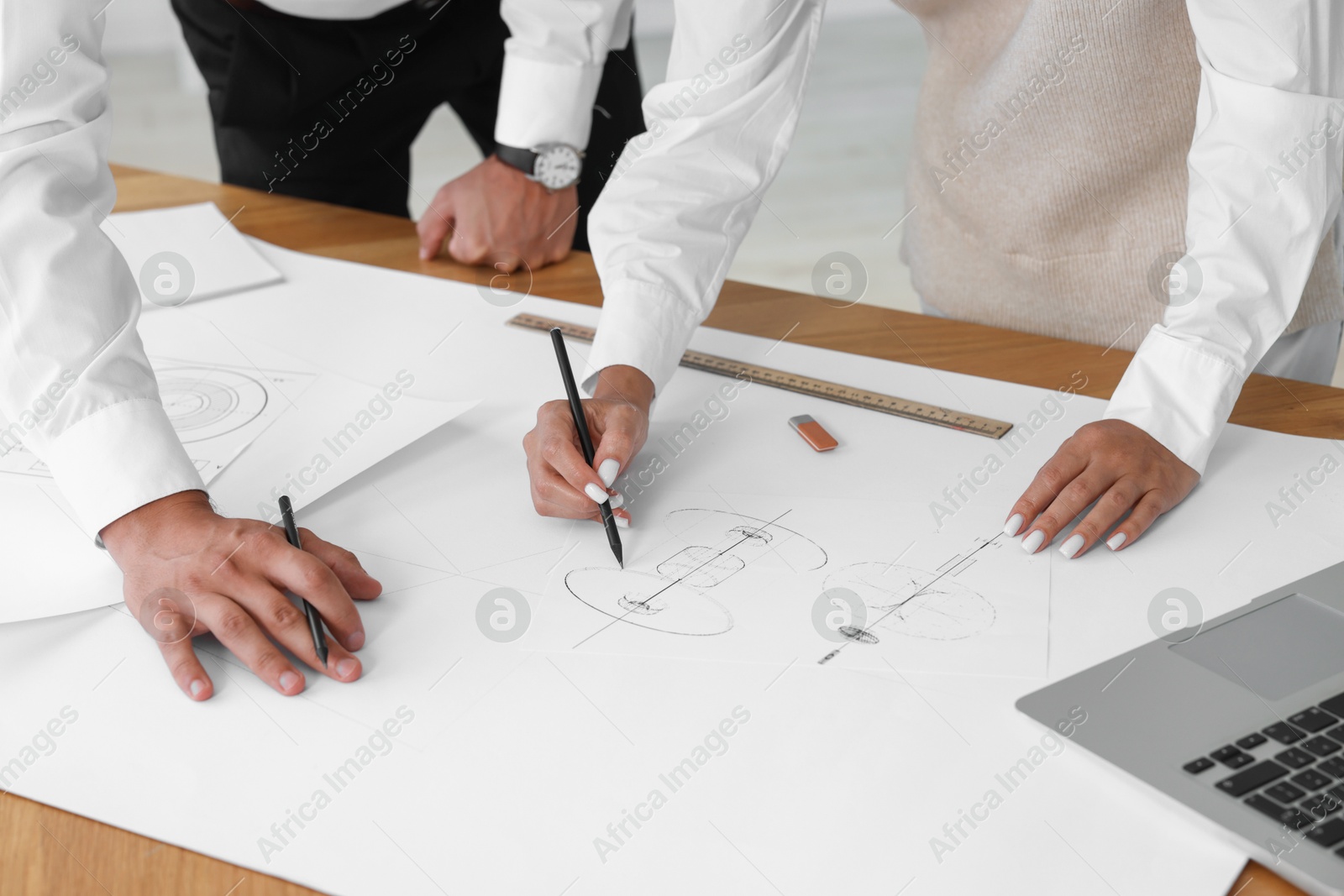 Photo of Architects making engineering drawing at wooden table in office, closeup